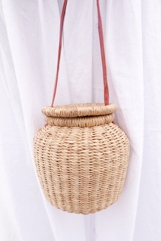 The natural Alobahe handbag is handwoven with straw called Kinkahe in Sherigu, Ghana. The shape is versatile and opens from the lid lifted vertical with an adjustable leather strap that can be worn as a crossbody or a handheld bag. This product supports a community with employment, educational opportunities for the children and improve the work environment.