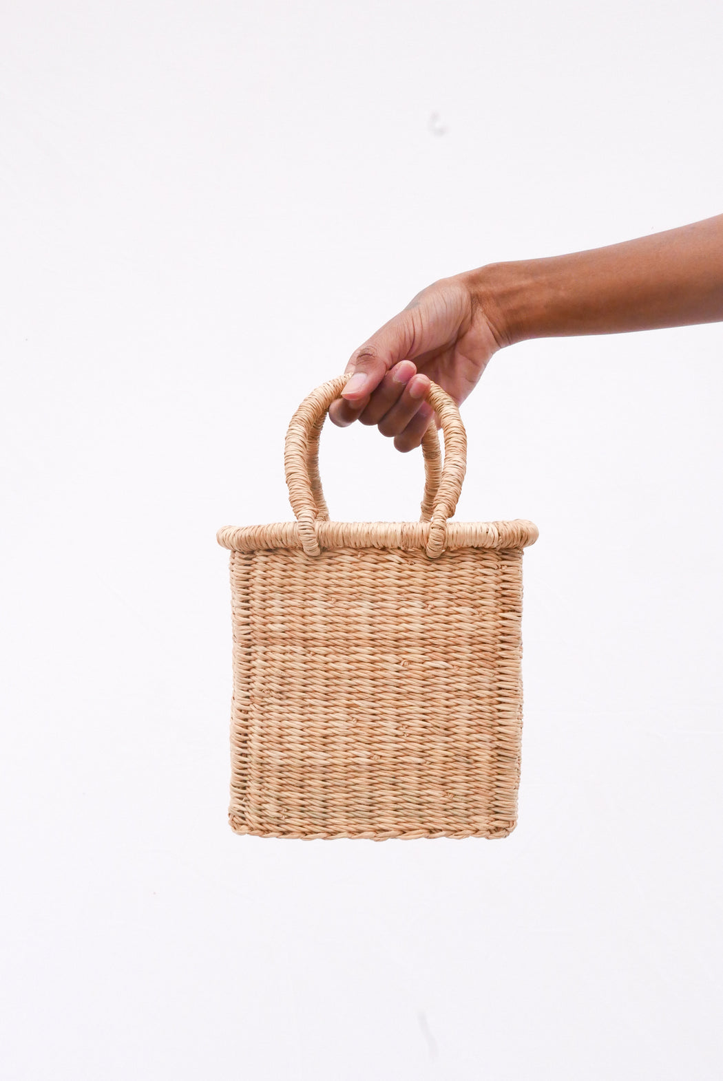 The Fuseini handbag is handwoven with straw called Kinkahe in Bolgatanga, Ghana. The shape is cube-like with two handles for durability. This product supports a community with employment, educational opportunities for the children and improve the work environment.