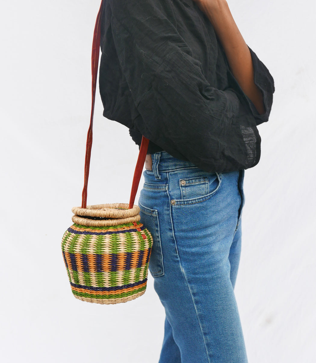 The multicolored Alobahe handbag is handwoven with straw called Kinkahe in Sherigu, Ghana. The shape is versatile and opens from the lid lifted vertical with an adjustable leather strap that can be worn as a crossbody or a handheld bag. This product supports a community with employment, educational opportunities for the children and improve the work environment.